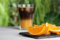 Tasty refreshing drink with coffee and orange juice on white table, focus on fruit slices