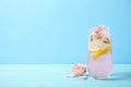 Tasty refreshing lemon drink with roses on wooden table against light blue background