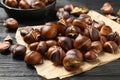 Tasty roasted edible chestnuts on black wooden table, closeup Royalty Free Stock Photo