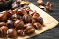 Tasty roasted edible chestnuts on black wooden table, closeup Royalty Free Stock Photo