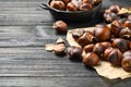 Tasty roasted edible chestnuts on black wooden table, closeup. Space for text Royalty Free Stock Photo