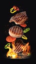 Tasty roasted meat and vegetables falling on barbecue grill with burning fire against background