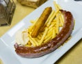 Tasty rustic sausage with french fries served at plate with white sauce