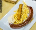 Tasty rustic sausage with french fries served at plate with white sauce