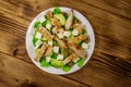 Tasty salad with fried chicken breast, green olives, feta cheese, avocado, lettuce and olive oil on wooden table. Top view Royalty Free Stock Photo