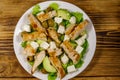 Tasty salad with fried chicken breast, green olives, feta cheese, avocado, lettuce and olive oil on wooden table. Top view Royalty Free Stock Photo
