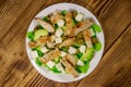 Tasty salad with fried chicken breast, green olives, feta cheese, avocado, lettuce and olive oil on wooden table. Top view Royalty Free Stock Photo