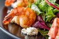 Tasty salad with tiger shrimps, lettuce, salad and philadelphia cheese on black plate. Close up with selective focus