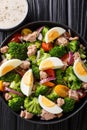 Tasty salad with tuna, broccoli, tomatoes, onions and eggs close-up in a plate. Vertical top view Royalty Free Stock Photo