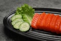 Tasty salmon slices, cucumber and lettuce on grey table, closeup. Delicious sashimi dish