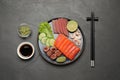 Tasty salmon slices, shrimp, cucumber, soy sauce and tuna on black table, flat lay. Delicious sashimi dish Royalty Free Stock Photo