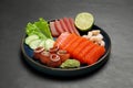 Tasty salmon slices, shrimp, cucumber and tuna on black table. Delicious sashimi dish Royalty Free Stock Photo