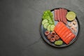 Tasty salmon slices, shrimp, cucumber and tuna on black table, top view with space for text. Delicious sashimi dish Royalty Free Stock Photo