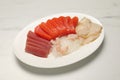 Tasty salmon slices, shrimp, funchosa and tuna on white marble table. Delicious sashimi dish