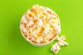 Tasty salty popcorn in paper cup on bright green background Royalty Free Stock Photo