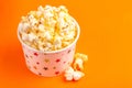 Tasty salty popcorn in paper cup on bright orange background Royalty Free Stock Photo
