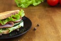 Tasty sandwich with ham, green salad, cucumbers and tomatoes on the wooden Royalty Free Stock Photo