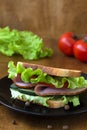 Tasty sandwich with ham, green salad, cucumbers and tomatoes on the wooden Royalty Free Stock Photo