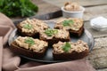 Tasty sandwiches with cod liver and parsley on wooden table