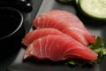 Tasty sashimi (pieces of fresh raw tuna) on black plate, closeup