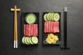 Tasty sashimi sets (pieces of fresh raw tuna), sliced cucumber, wasabi sauce and ginger slices on black table, flat lay Royalty Free Stock Photo