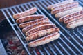 Tasty sausages sizzling on a portable BBQ fire grilling over the flames on a summer picnic, close up view.preparing bbq Royalty Free Stock Photo
