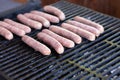 Tasty sausages sizzling on a portable BBQ fire grilling over the flames on a summer picnic, close up view.preparing bbq Royalty Free Stock Photo