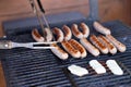 Tasty sausages sizzling on a portable BBQ fire grilling over the flames on a summer picnic, close up view.man preparing Royalty Free Stock Photo