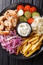 Tasty shawarma bowl with chicken, french fries, vegetables and sauce close-up. Vertical top view