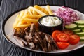 Tasty shawarma bowl with lamb, french fries, vegetables and sauce close-up. Horizontal