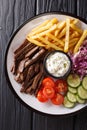 Tasty shawarma bowl with lamb, french fries, vegetables and sauce close-up. Vertical top view Royalty Free Stock Photo