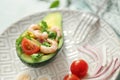 Tasty shrimp salad in avocado boat on plate, closeup