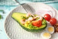 Tasty shrimp salad in avocado boat on plate, closeup