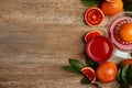 Tasty sicilian orange juice in glass, squeezer and fruits on wooden table, flat lay. Space for text