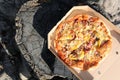 Tasty pizza on a paper box lying on a wooden stump