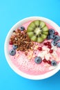 Tasty smoothie bowl with fresh kiwi fruit, berries and granola on light blue background, top view Royalty Free Stock Photo