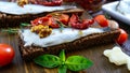 Tasty smorrebrod on a wooden board. Sandwiches with black rye bread, sun-dried tomatoes, salted anchovies, mustard Royalty Free Stock Photo