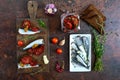 Tasty smorrebrod on a wooden board. Sandwiches with black rye bread, sun-dried tomatoes, salted anchovies, mustard. Top view Royalty Free Stock Photo