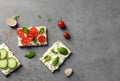 Tasty snacks with cream cheese and vegetables on gray table, flat lay.