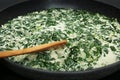 Tasty spinach dip with wooden spoon in frying pan, closeup Royalty Free Stock Photo