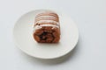 Tasty Sponge cake roll with chocolate, vanilla and berry cream, in plate isolated on white backdrop Royalty Free Stock Photo