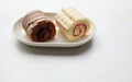 Tasty Sponge cake roll with chocolate, vanilla and berry cream, in plate isolated on white backdrop Royalty Free Stock Photo