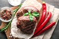 Tasty steaks with chili peppers and herbs on board Royalty Free Stock Photo