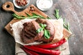 Tasty steaks with chili peppers and herbs on board Royalty Free Stock Photo