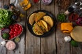 Tasty street tacos with beef, tomatoes, onion and cheese on black round plate. Ingredients for cooking tacos on rustic wooden Royalty Free Stock Photo