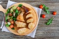 Tasty stuffed chicken legs with salad of fresh vegetables on a wooden background. Royalty Free Stock Photo