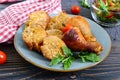 Tasty stuffed chicken legs with salad of fresh vegetables on a wooden background.