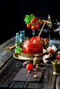 Tasty sun dried tomatoes with garlic, pepper, basil, olive oil in glass jar stands on brass plates on rustic wooden table Royalty Free Stock Photo