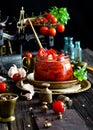 Tasty sun dried tomatoes with garlic, pepper, basil, olive oil in glass jar stands on brass plates on rustic wooden table Royalty Free Stock Photo