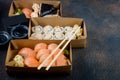 Tasty sushi rolls in disposable kraft paper boxes, sauces, chopsticks. Food for take away or delivery Royalty Free Stock Photo